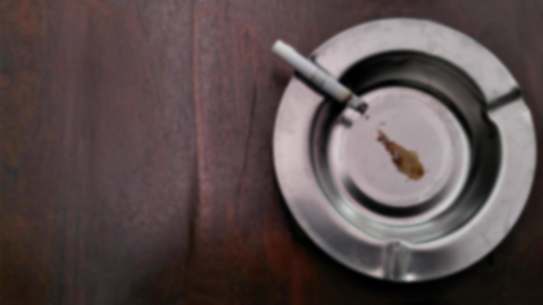 Defocused background cigarettes and ashtray on vintage wooden table with copy text space. photo