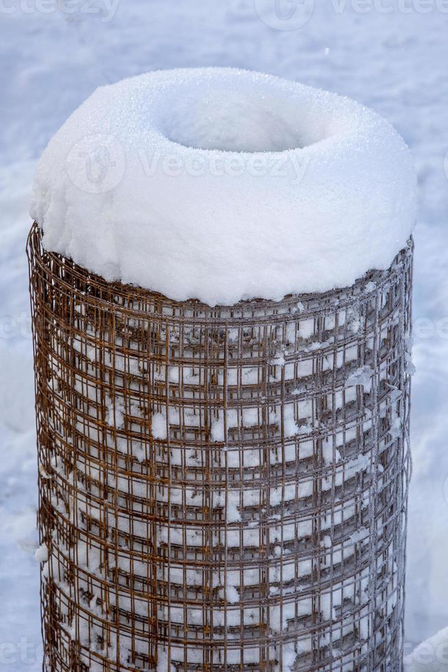 metal bajo la nieve. rollo de malla de alambre. Almacenamiento de estructuras metálicas en invierno. foto