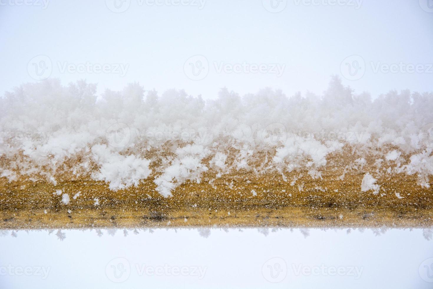 Snow on the pipe. Snowflakes lie on a metal yellow pipe. photo
