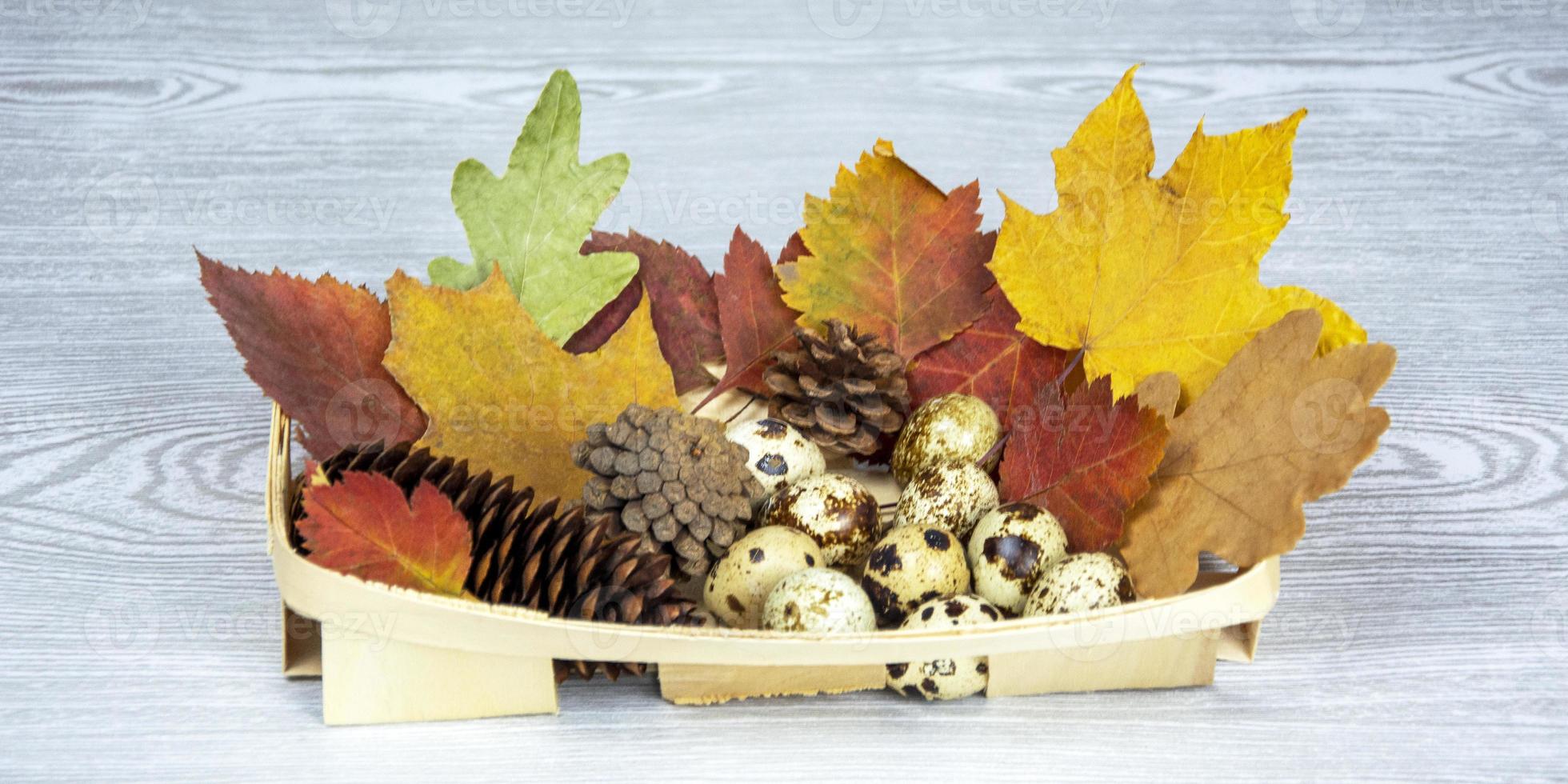 Easter eggs, leaves and cones in a wicker basket on a light wooden background. Postcard Happy Easter. Spring composition. photo