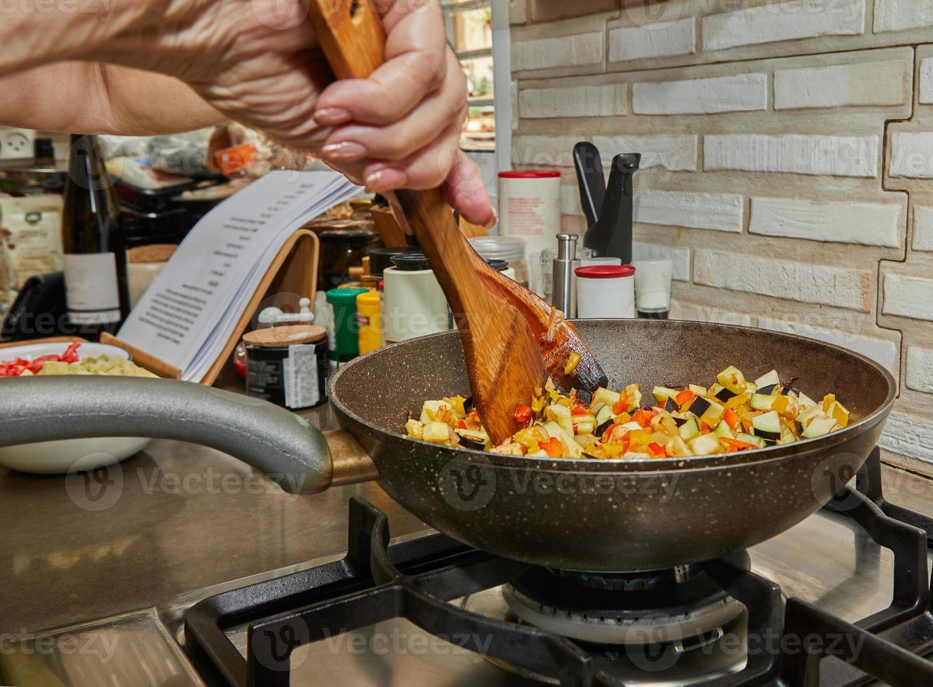 Stir eggplants, zucchini and bell peppers in skillet over low heat photo