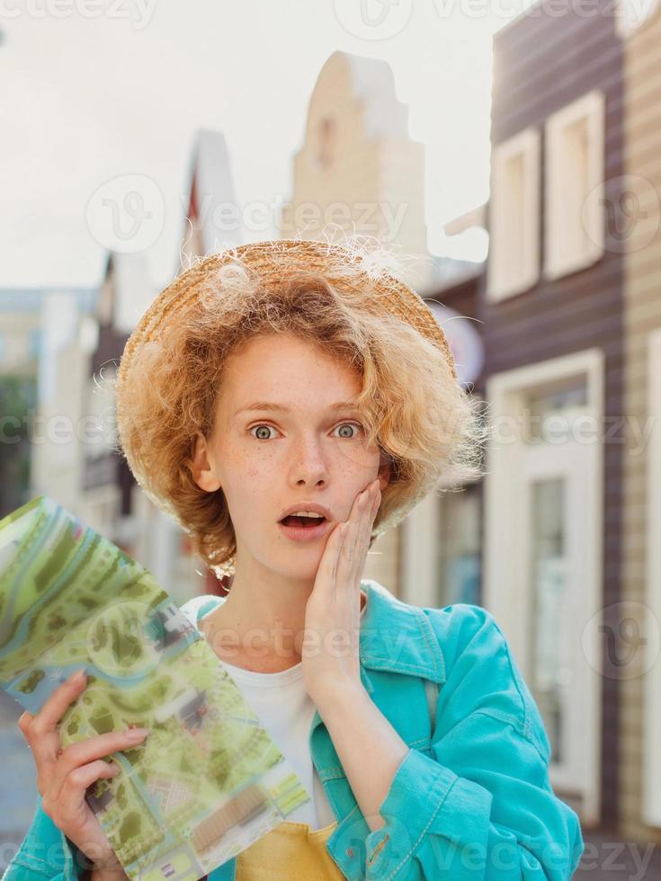 redhead young woman travel over West Europe and using paper map in unknown town. Travel photo. Lost in new city photo