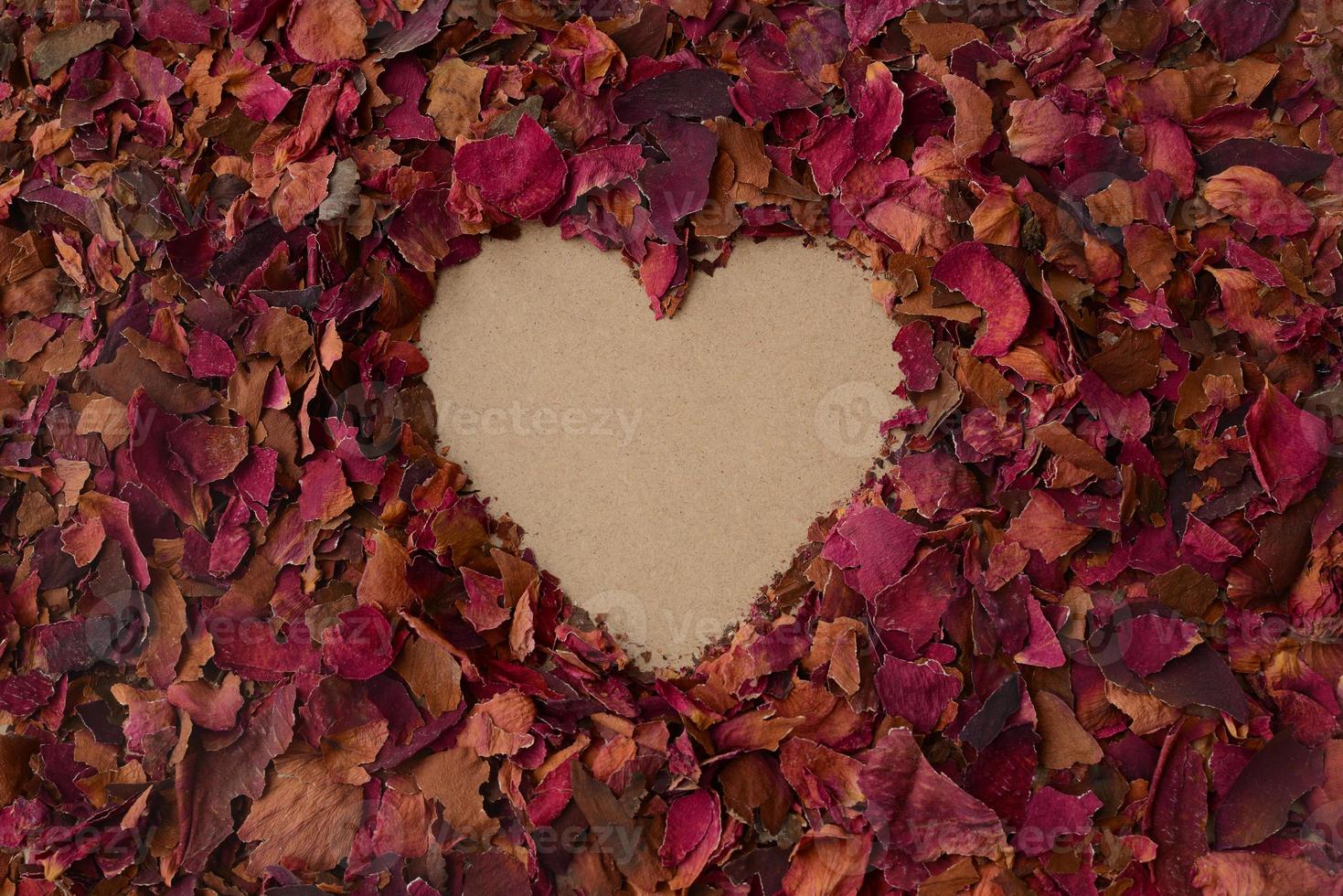 Heart shape in a background of dried red rose petals. Love backdrop, Valentines day card, copy space photo