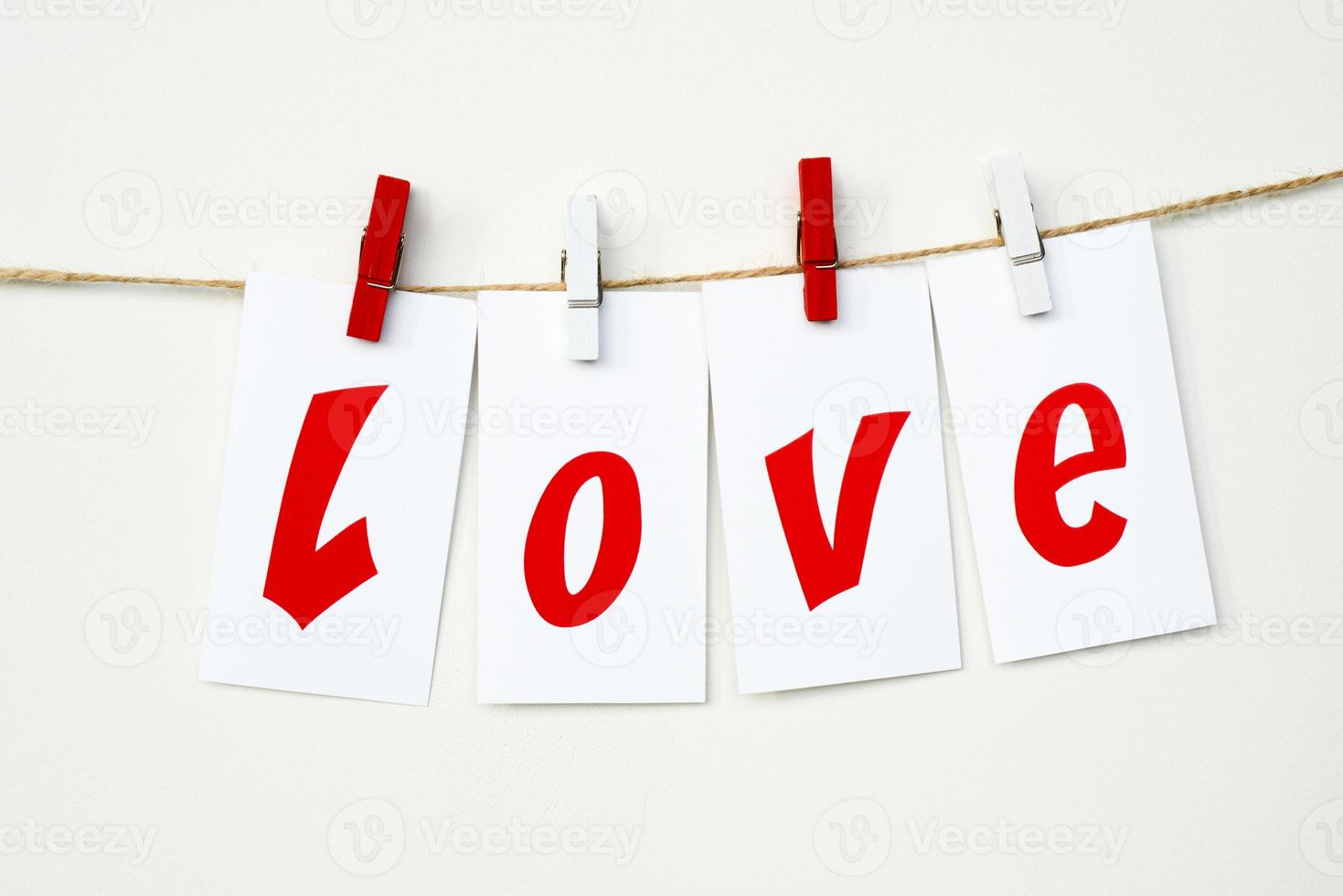 Cards with red word LOVE hang on a rope on clothespins on a white background. Valentine's Day photo