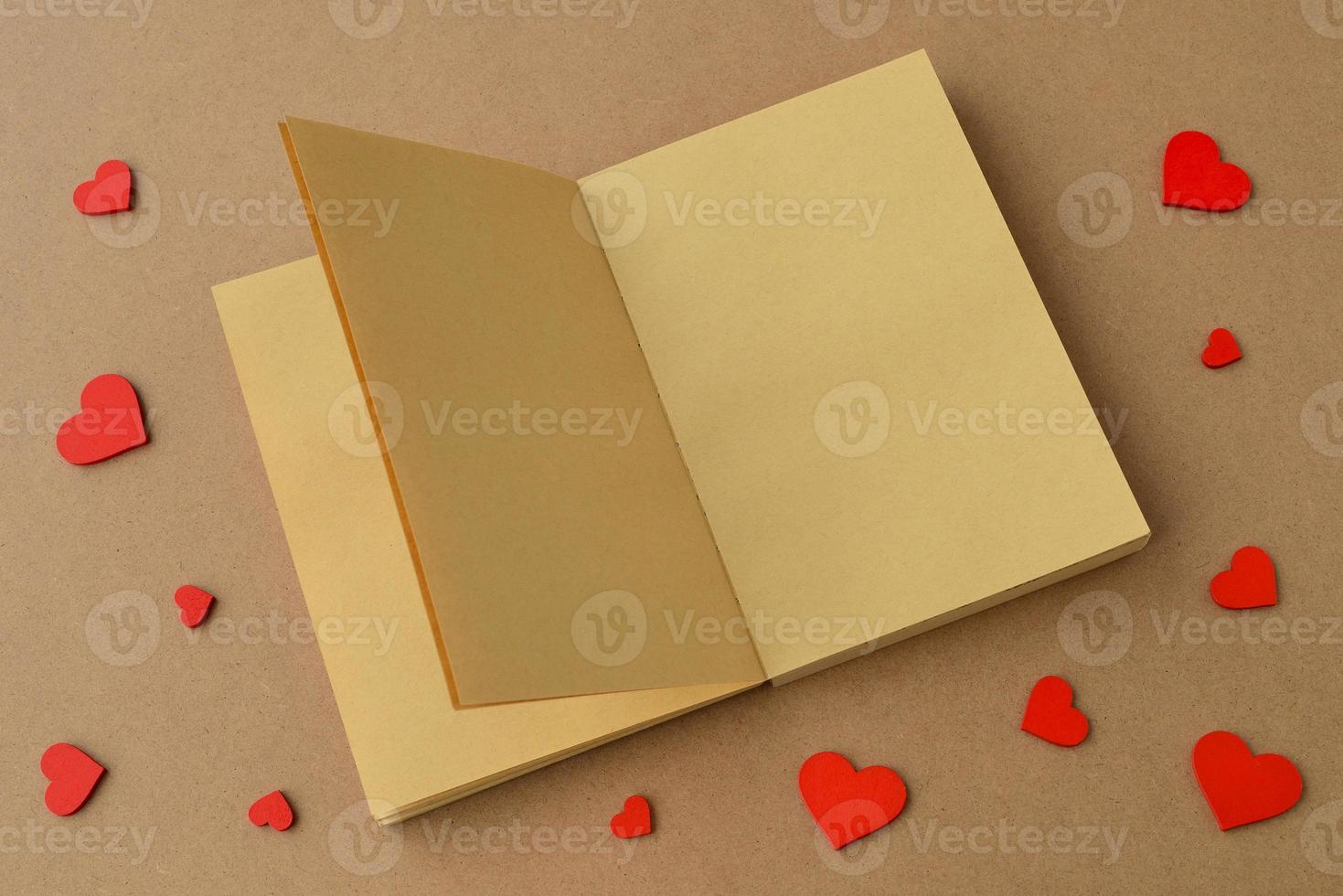 Open book or notebook made of kraft paper, red hearts on table. Valentines day, Valentine card, love photo