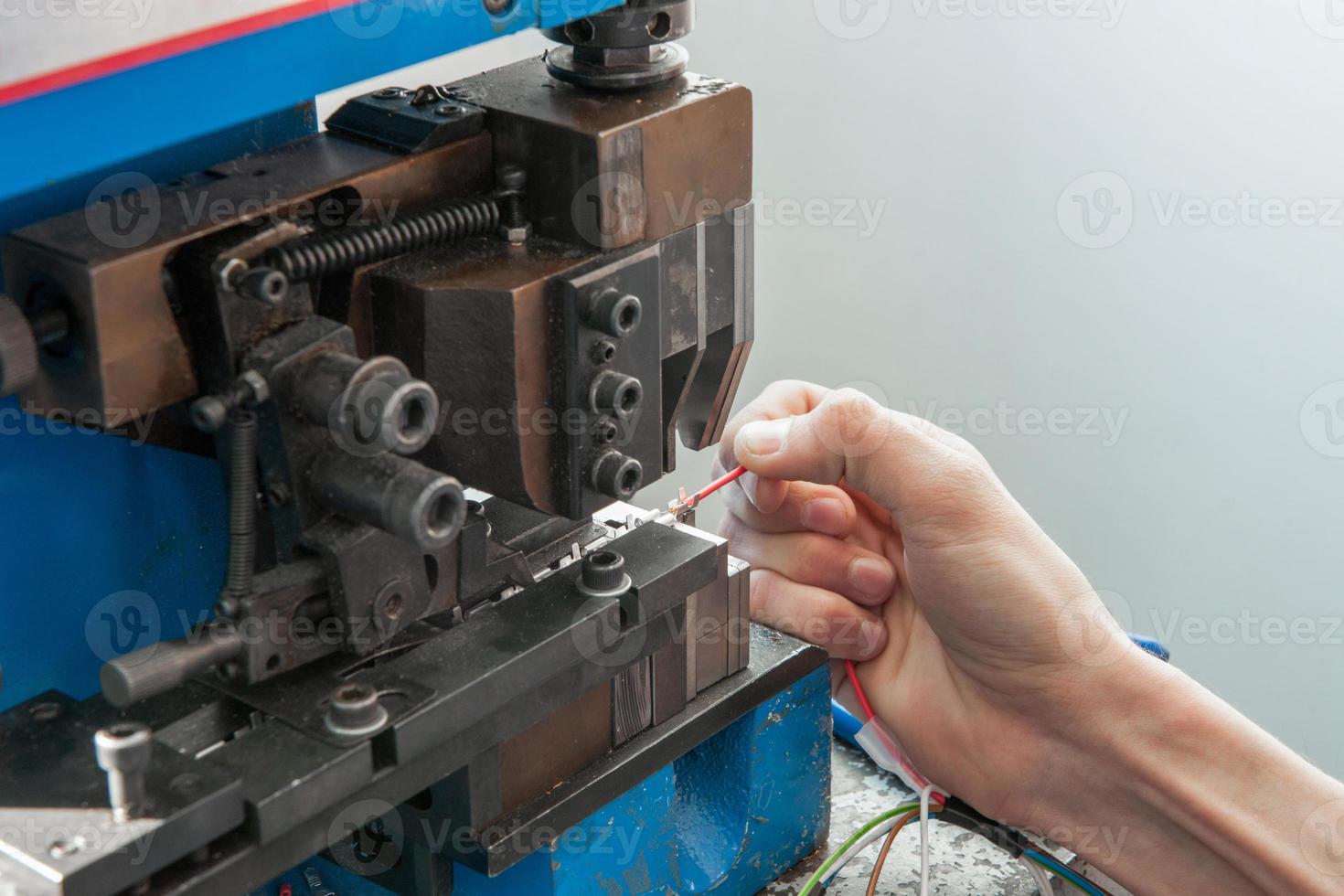hands working behind the machine for assembling the cable with terminal connector photo