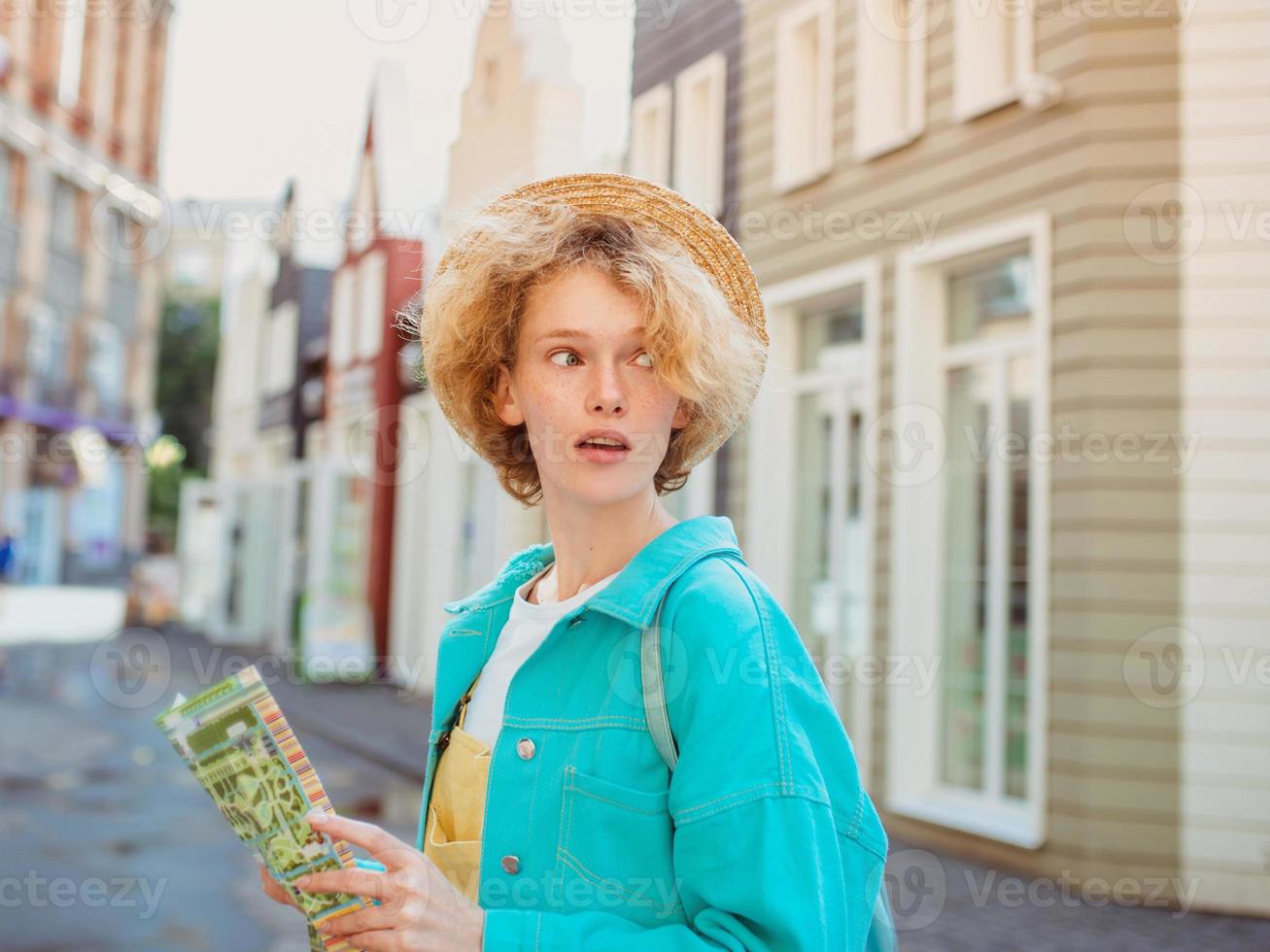 una joven pelirroja viaja por Europa occidental y usa un mapa de papel en una ciudad desconocida. foto de viaje perdido en nueva ciudad