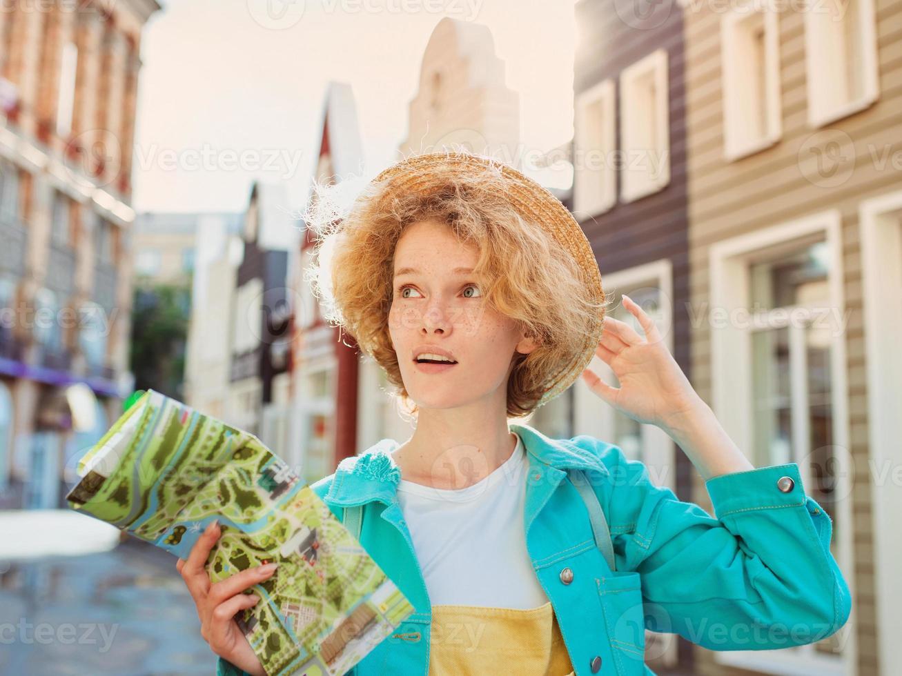 Portrait of redhead young woman in straw hat and with travel bag with paper map travel over West Europe. Travel and lifestyle photo