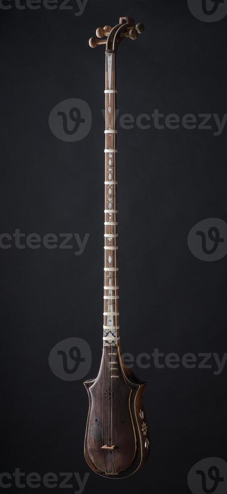 ancient Asian stringed musical instrument on black background with backlight photo