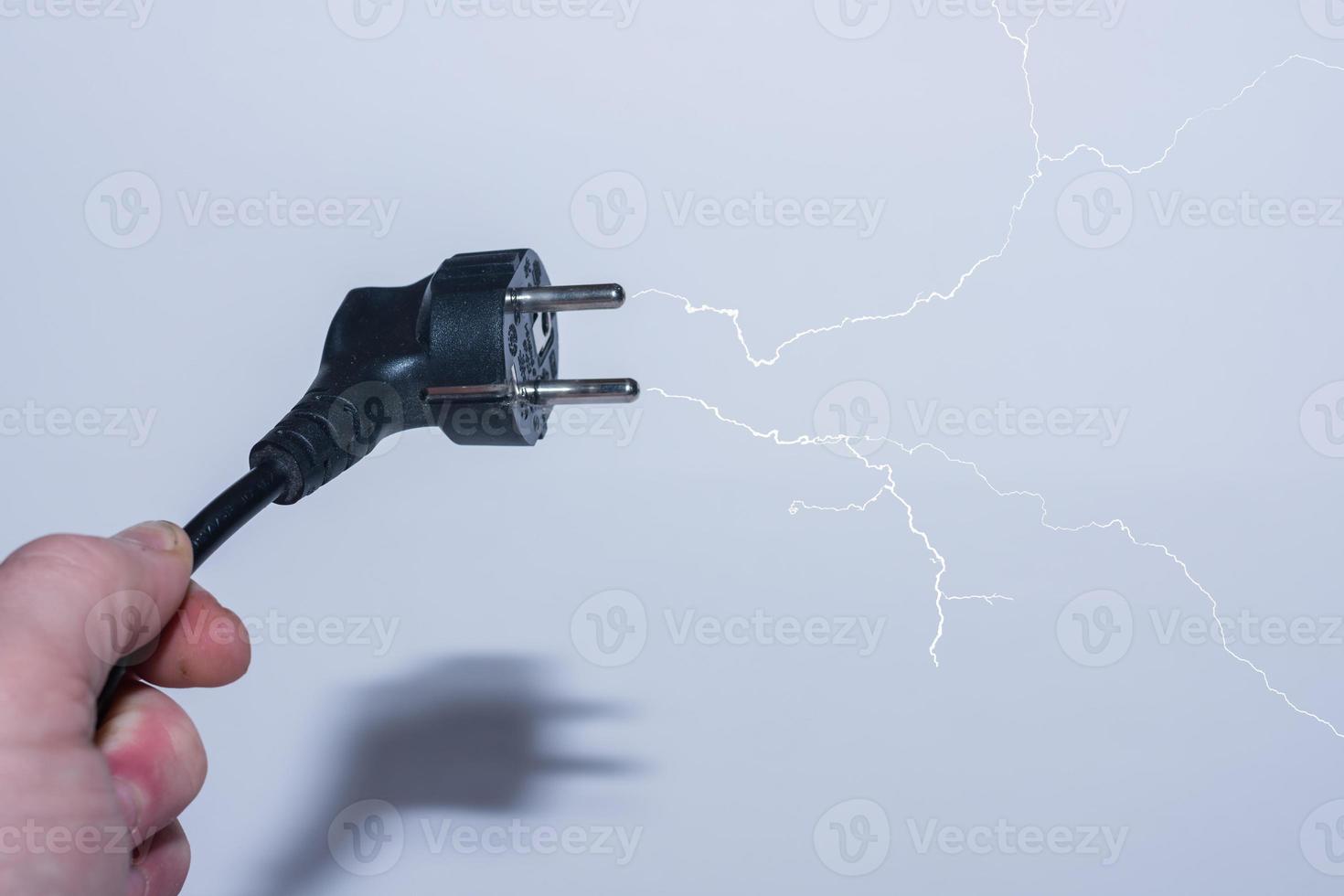 plug oblique in one hand save electricity and a branched lightning with gray photo