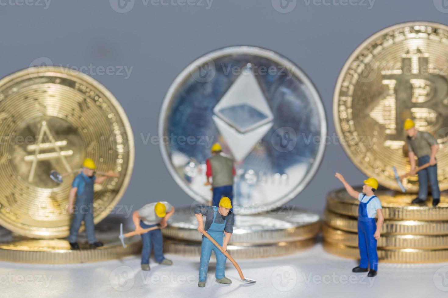 monedas criptográficas valiosas bitcoin ether y ada en una fila con muchos trabajadores en detalle de fondo gris foto