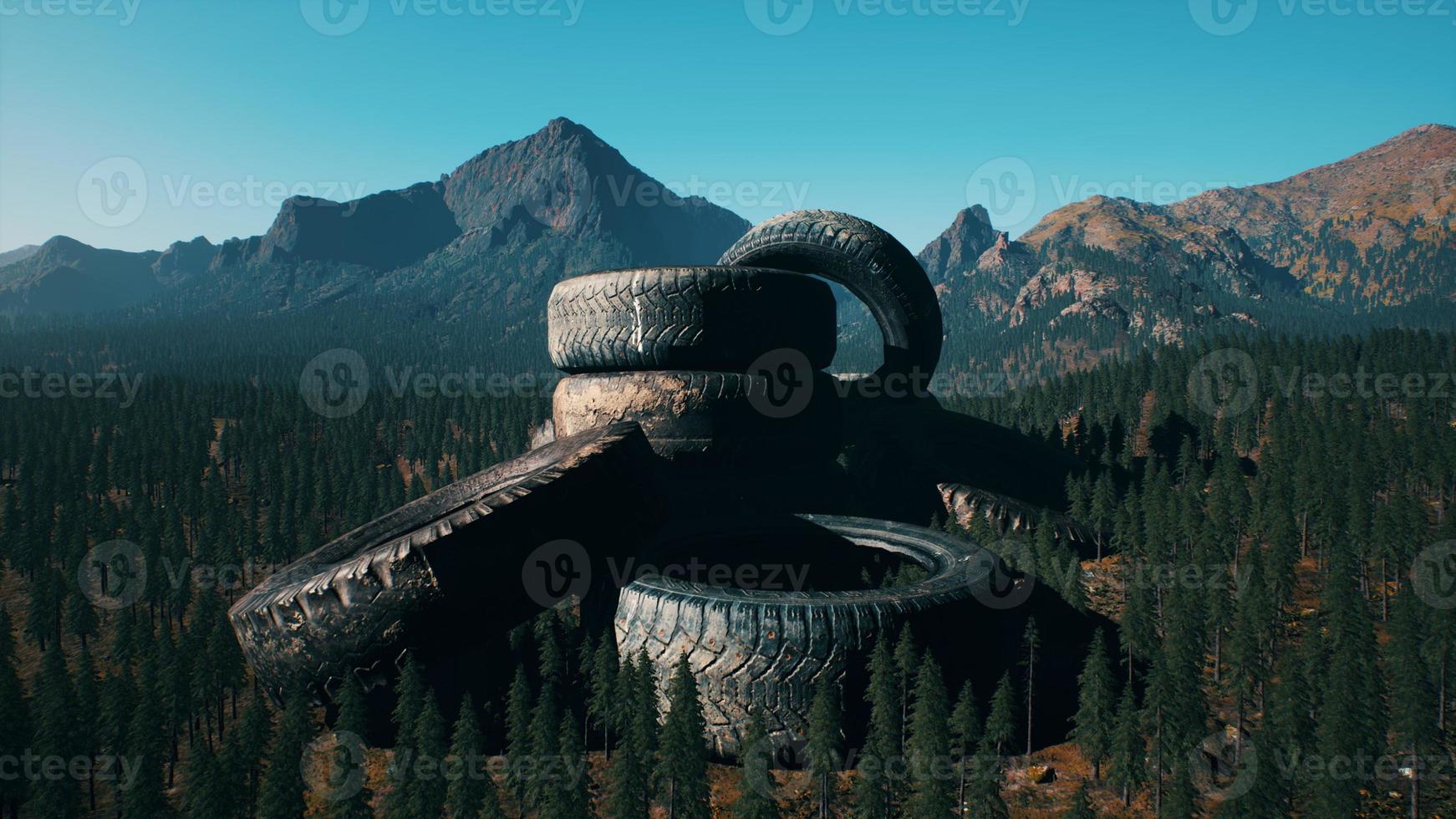 concept of environmental pollution with big old tires in mountain forest photo