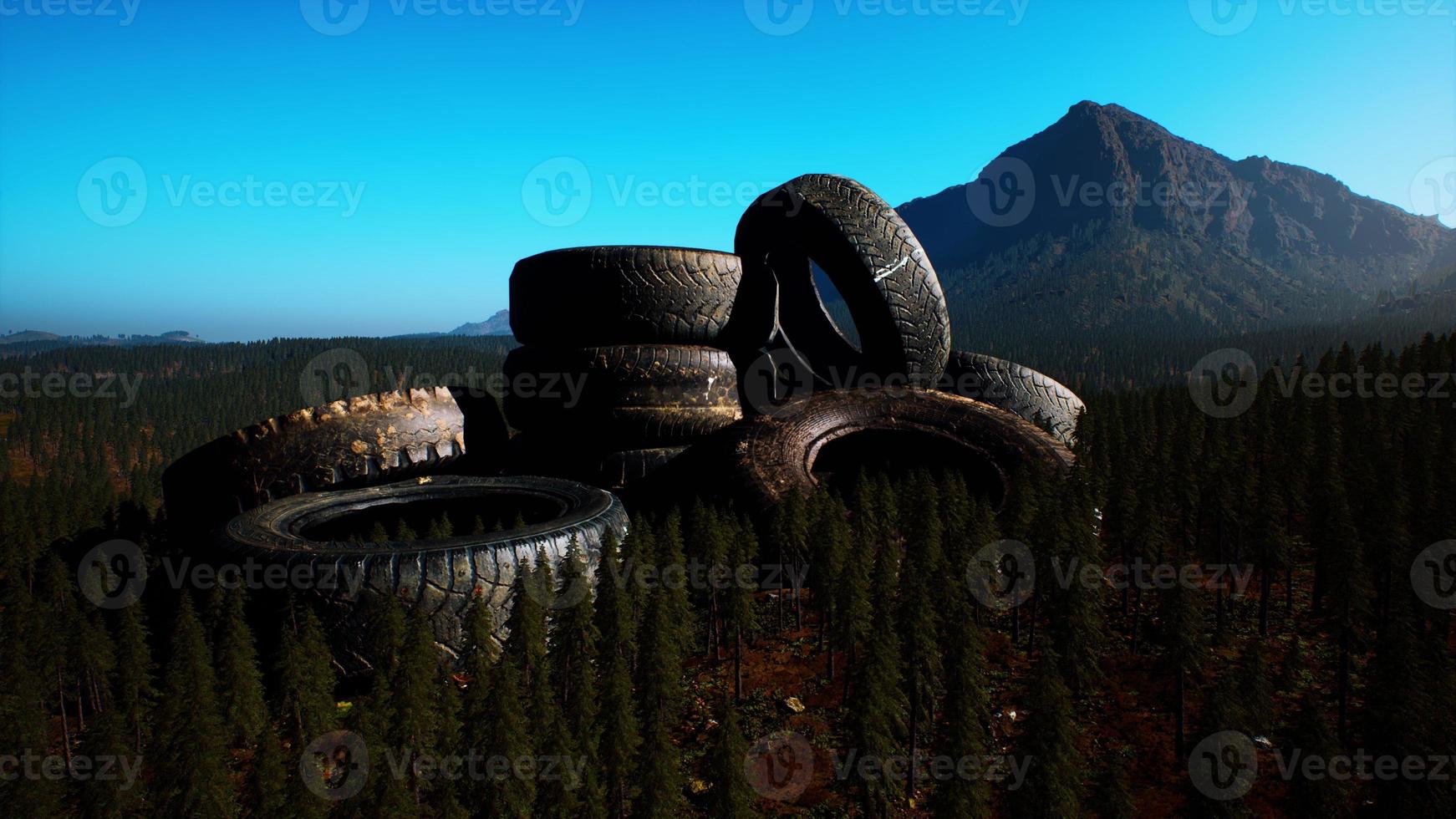 concept of environmental pollution with big old tires in mountain forest photo