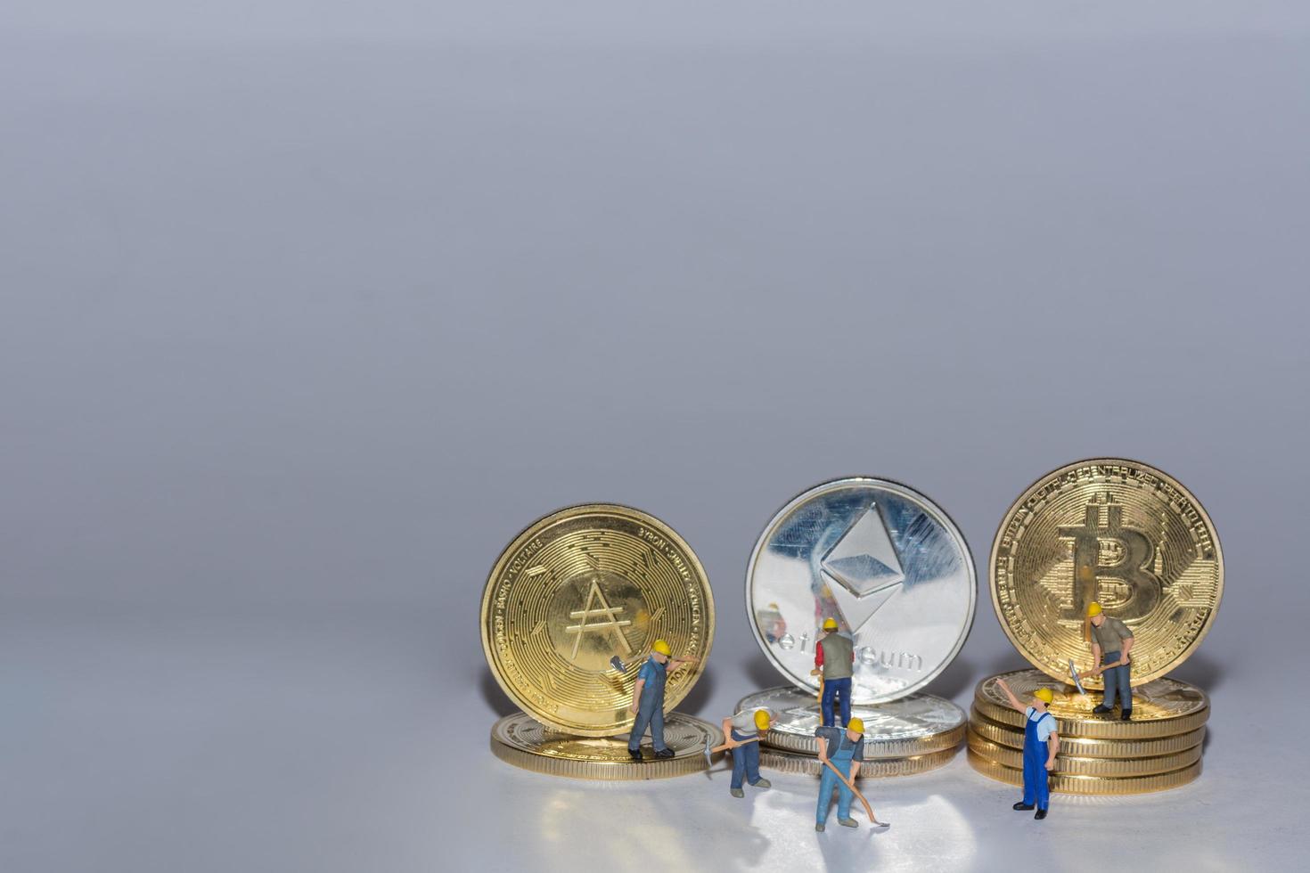 monedas criptográficas valiosas bitcoin ether y ada en una fila con muchos trabajadores sobre fondo gris en la parte inferior derecha foto