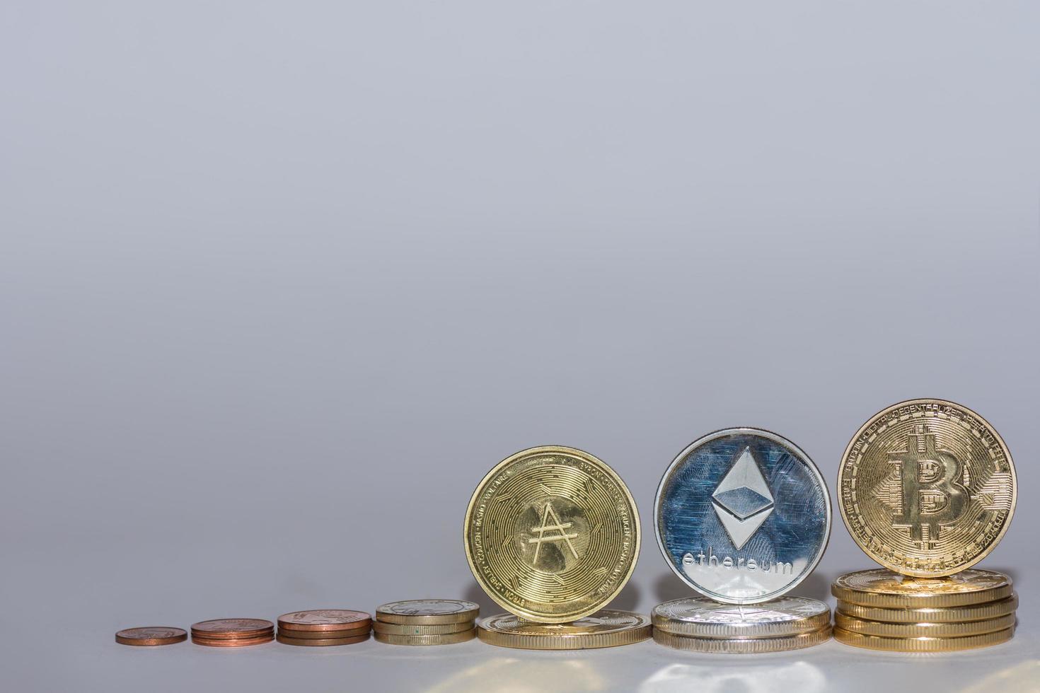 monedas de euro y monedas criptográficas bitcoin ether y ada en una fila con fondo gris recto foto