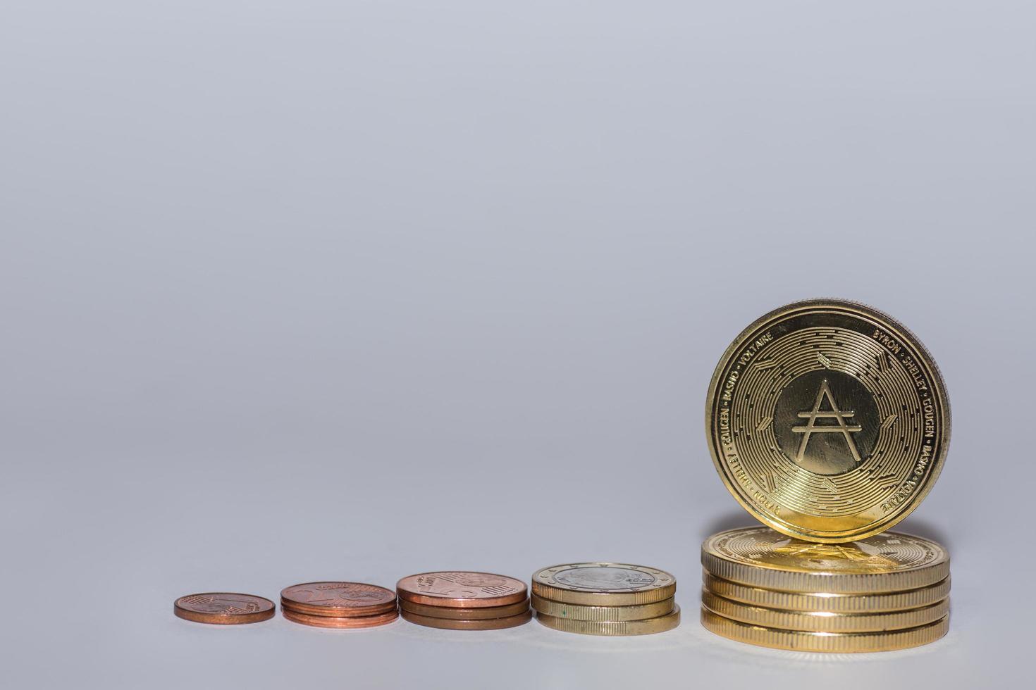 monedas de euro y monedas ada de moneda criptográfica apiladas en una fila con gris foto