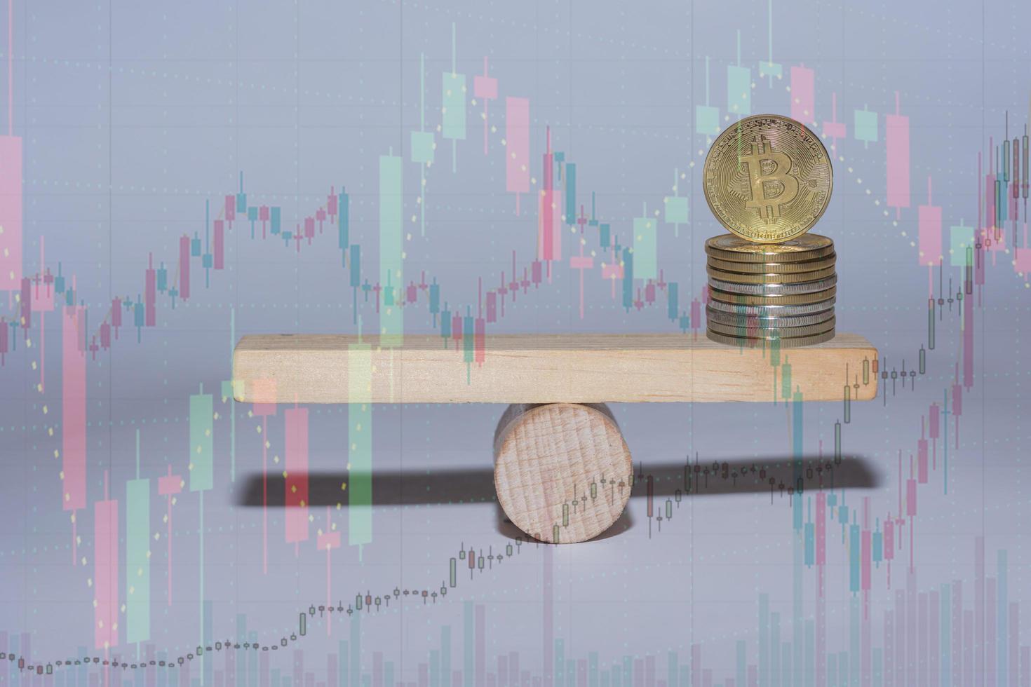 stacked bitcoin on a wooden seesaw with charts from the market photo