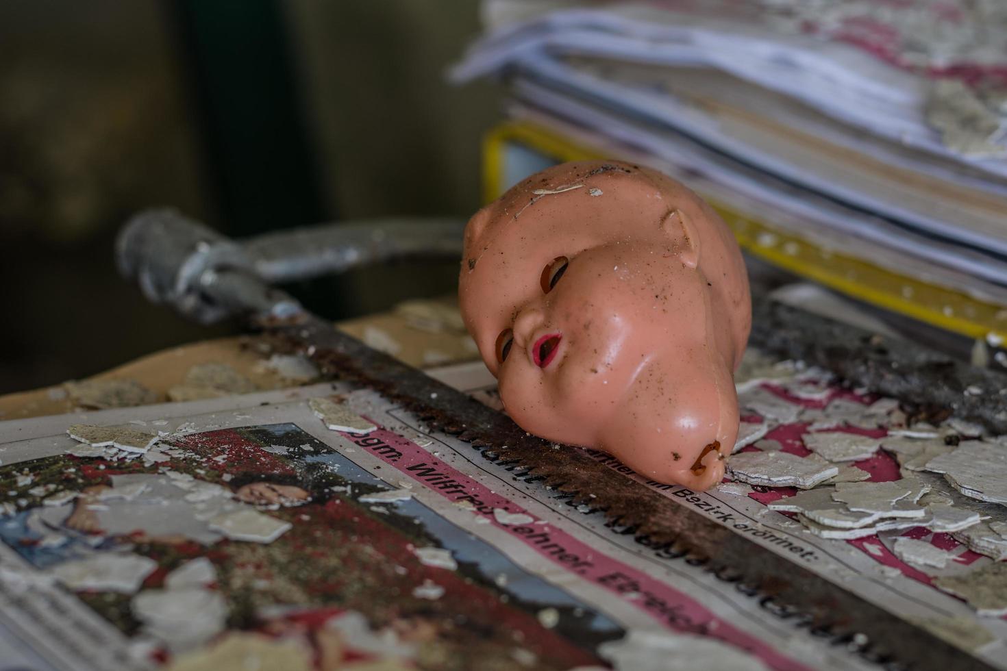 head from a doll on a rusty saw in a old house photo