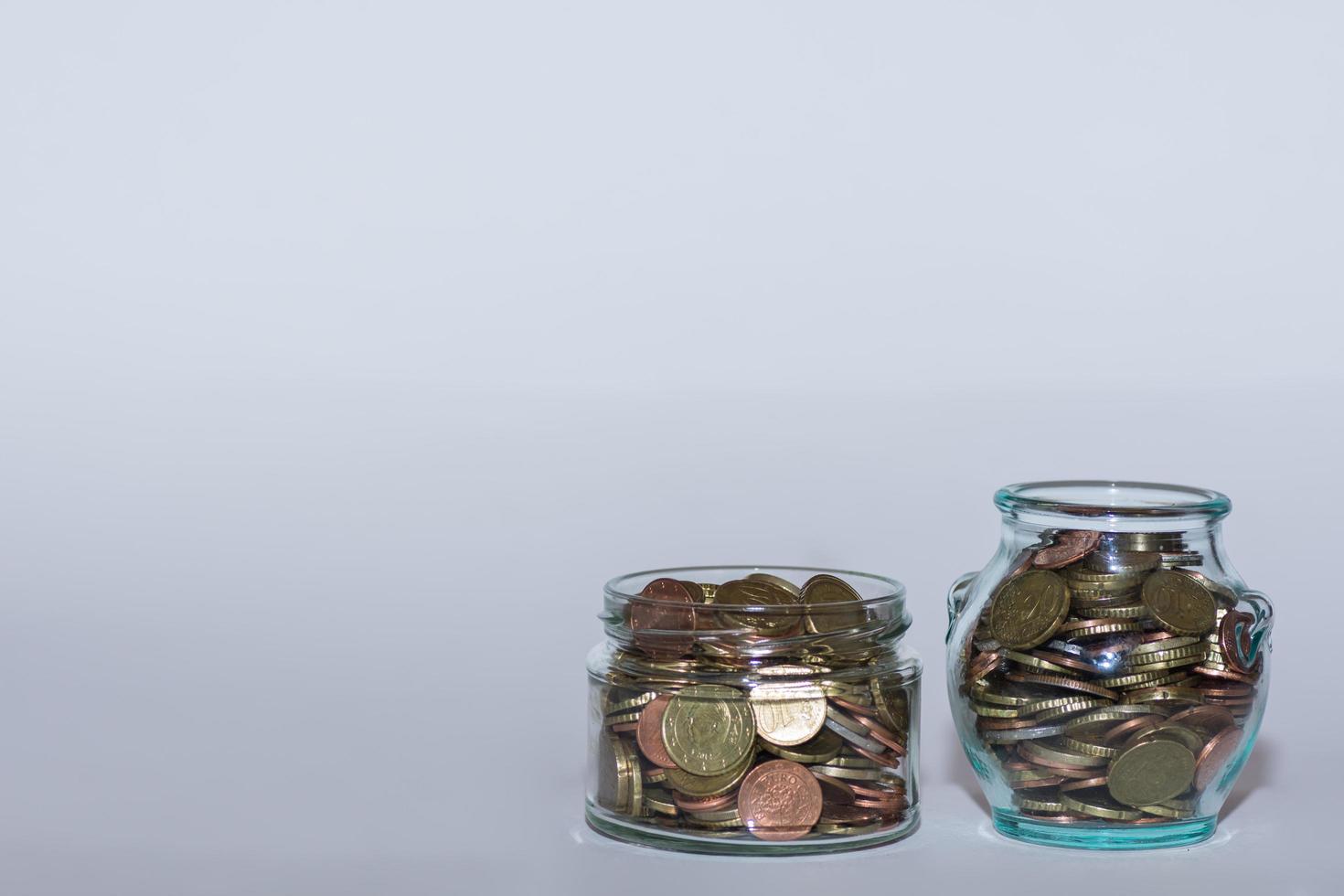 saved money in two  jars with many different euro coins for financial independence with gray photo