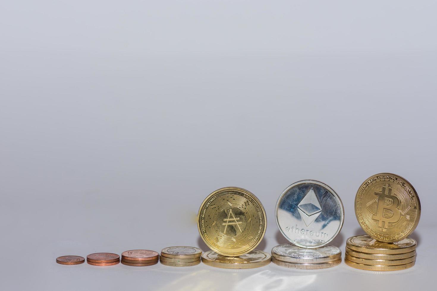 monedas de euro y monedas criptográficas bitcoin ether y ada en una fila con fondo gris oblicuo foto