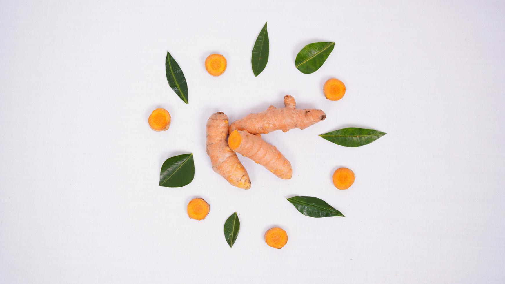 interestingly arranged pieces of turmeric and lime leaves isolated on white background photo