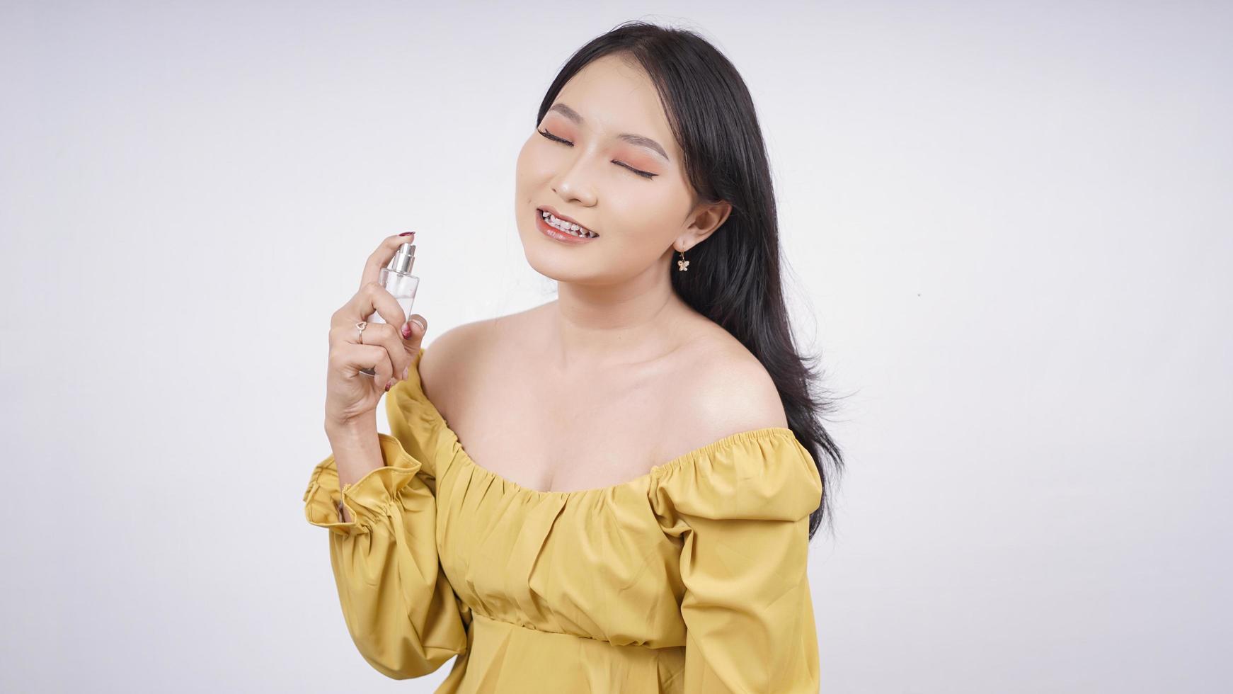 beautiful asian girl sprays perfume on her bed isolated on white background photo