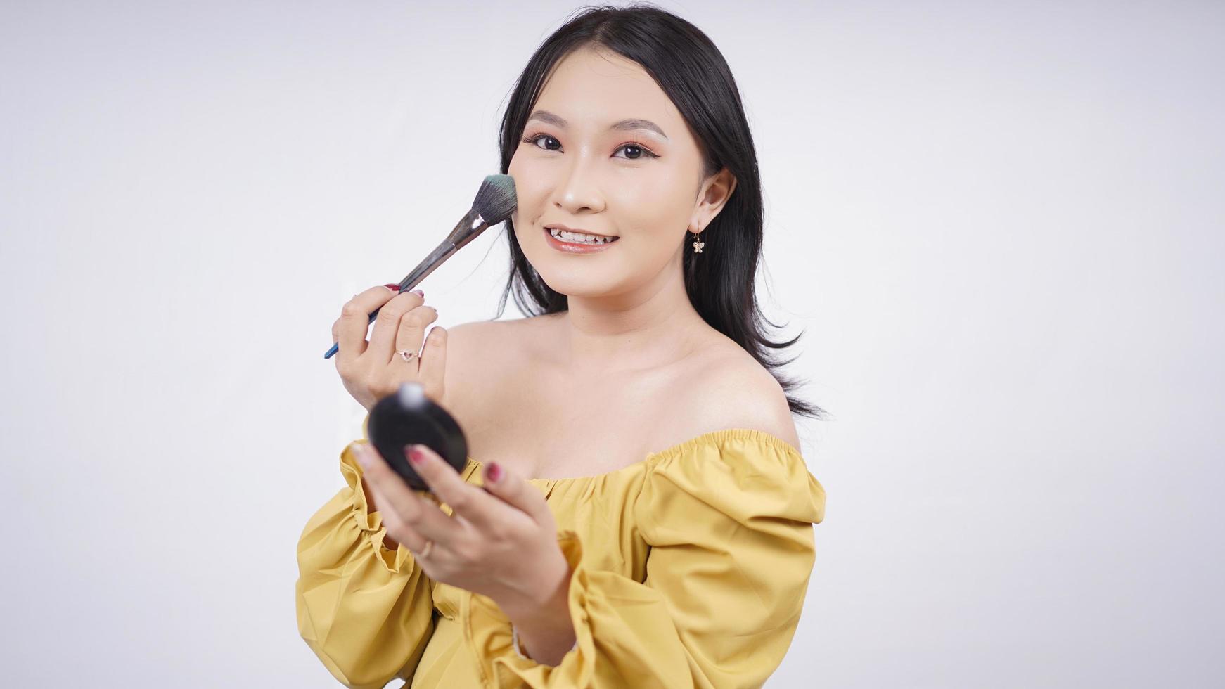 asian girl make up applying blush on cheek isolated on white background photo