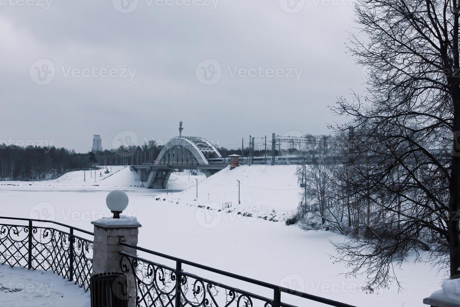 vista de un río congelado y un puente ferroviario en un invierno cubierto de nieve. foto