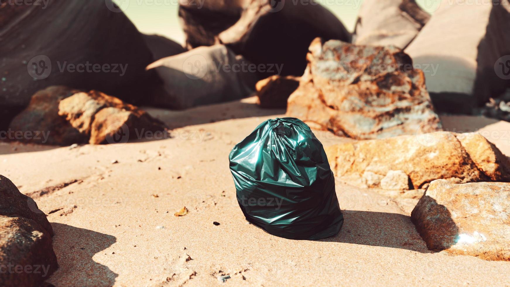 black plastic garbage bag full of trash on the beach photo