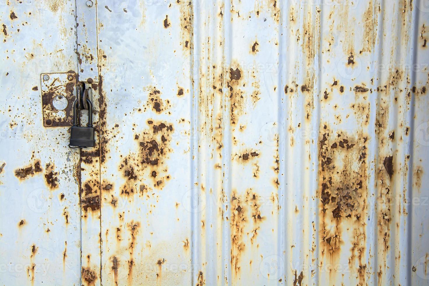 Old metal gate covered with rust with a new black lock. photo