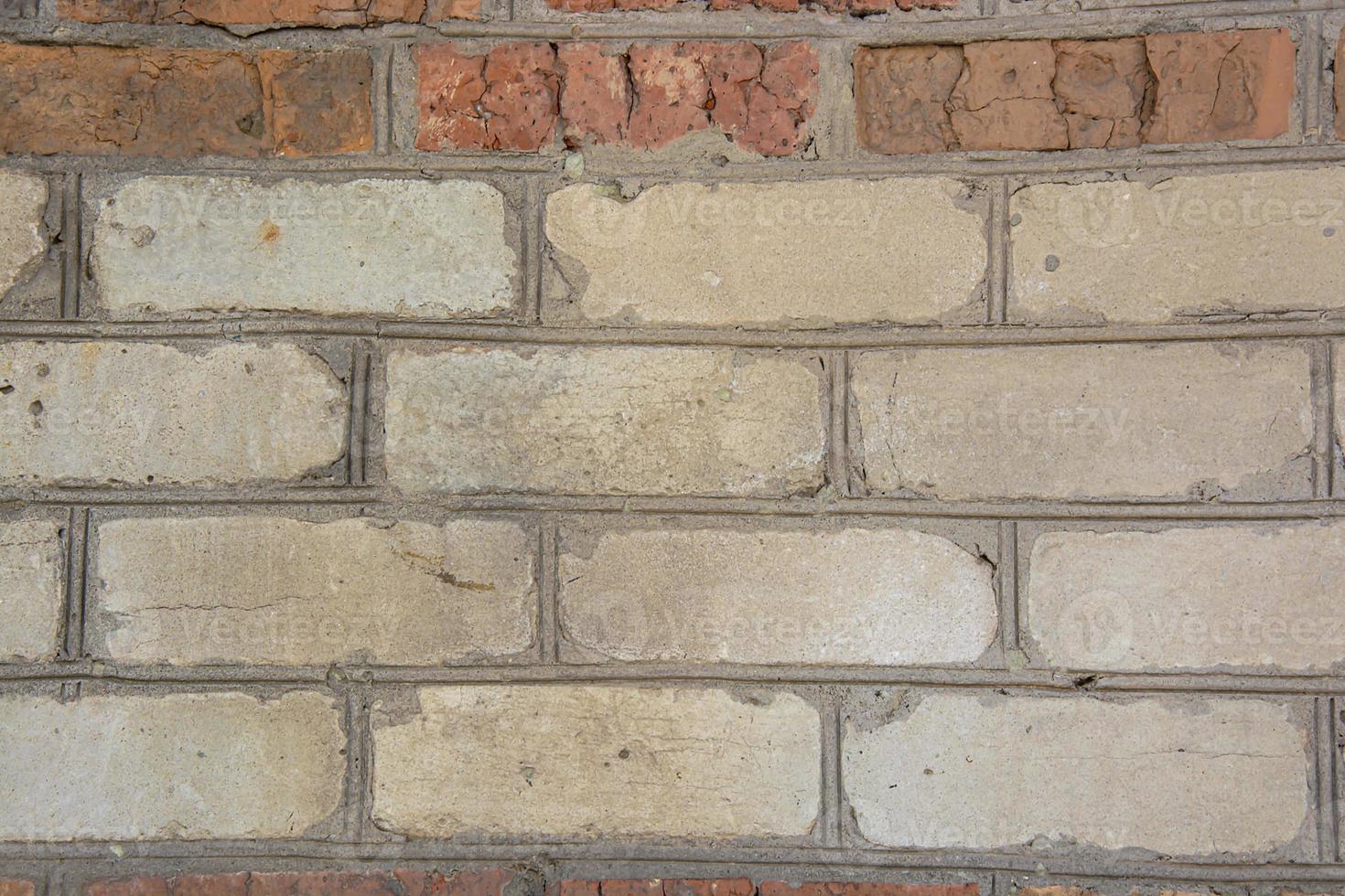 A crumbling wall of white and red bricks. Abstract background. Texture. photo
