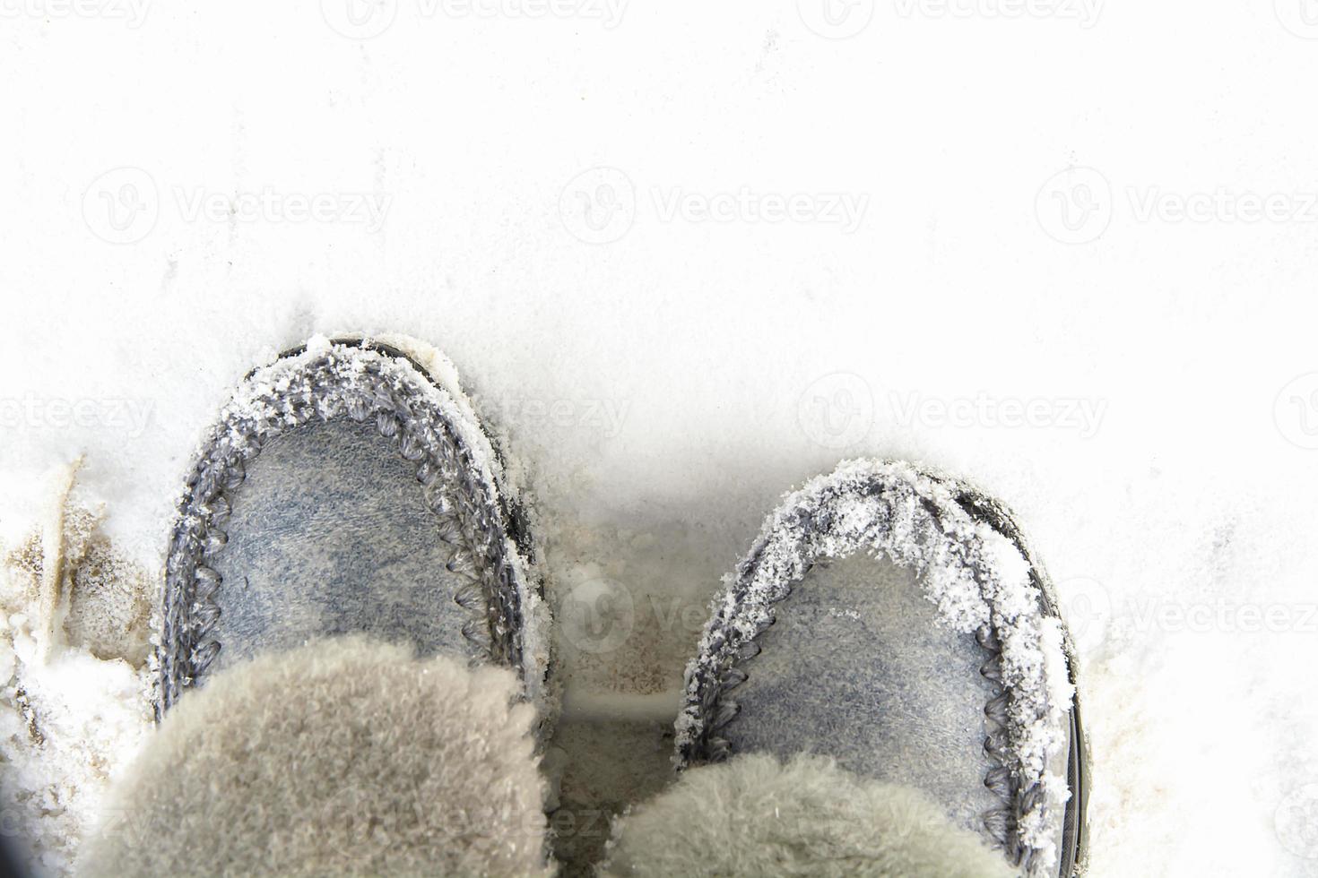 Warm winter women's boots of gray color with fur on a background of snow. photo