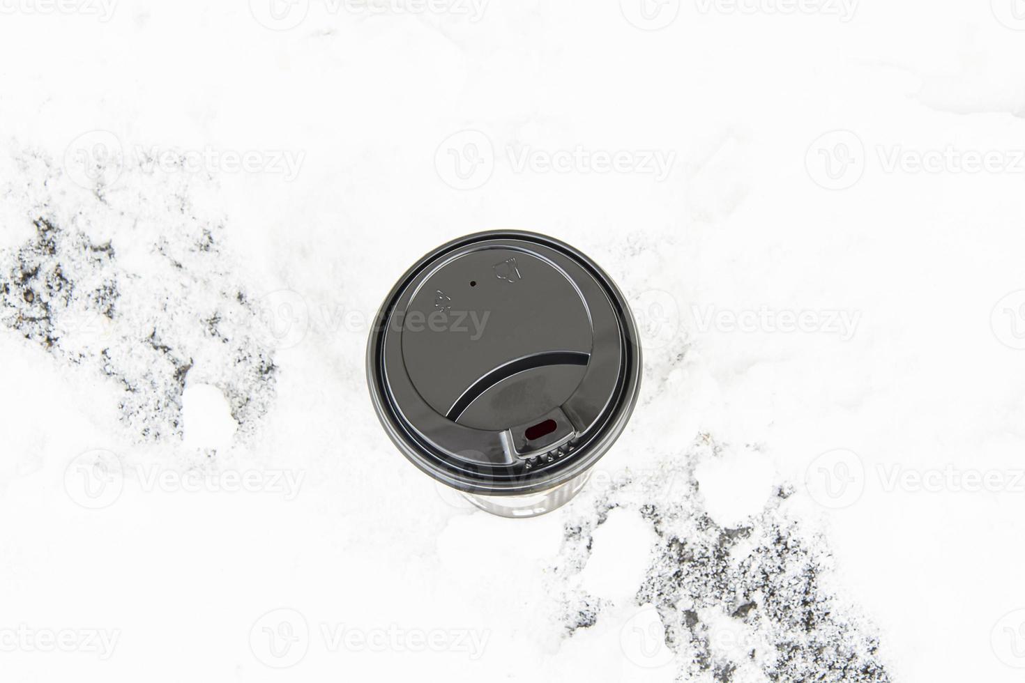 A large disposable paper cup with a lid for hot drinks on a snowy background. photo