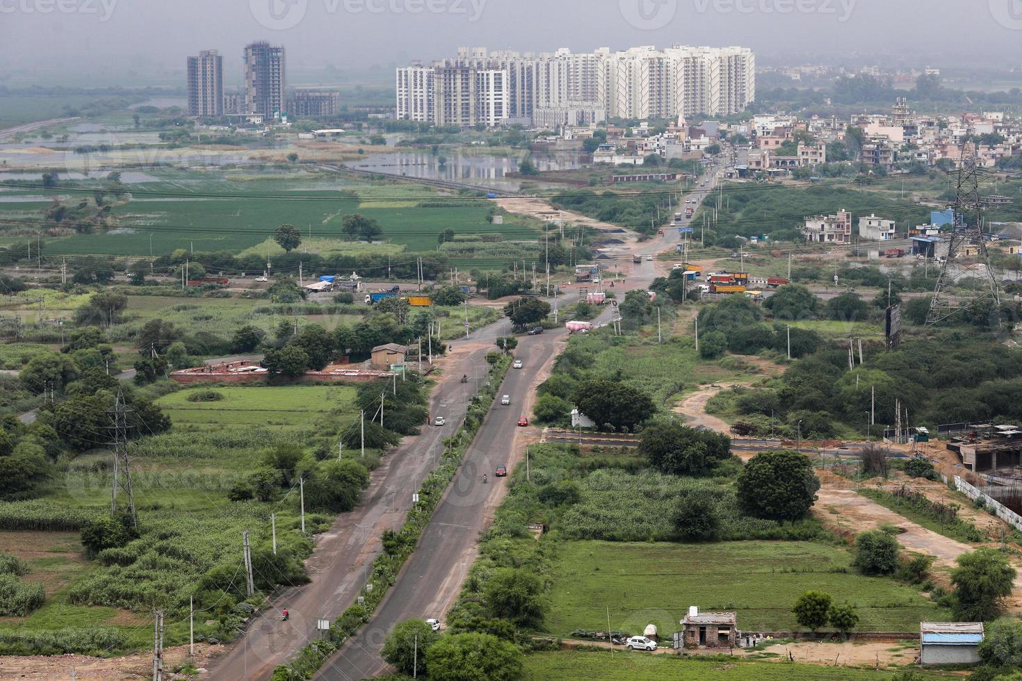 vista aérea del paisaje de una ciudad en desarrollo, afueras de delhi y gurugram. vista aérea de campos y torres. foto