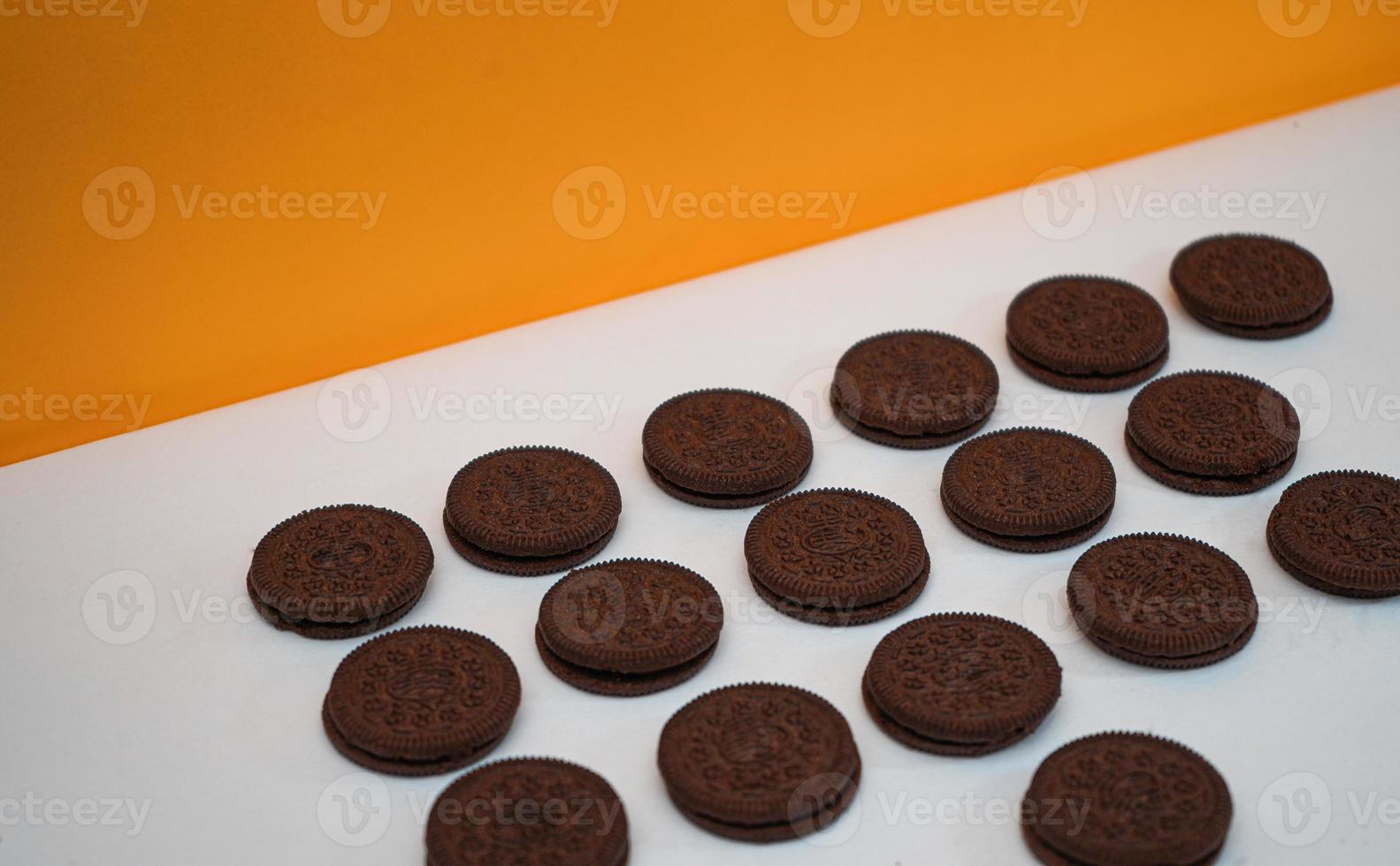 Chocolate cookies kept in a pattern on a white paper with a yellow background photo