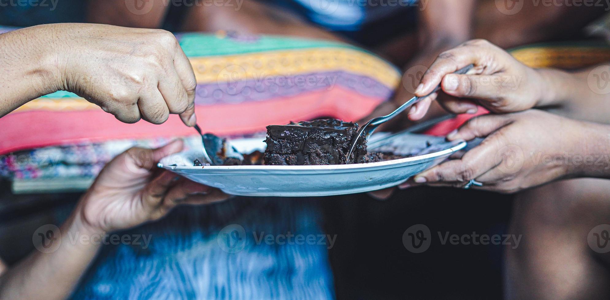 dos personas cortando un trozo de pastel de chocolate del plato. foto