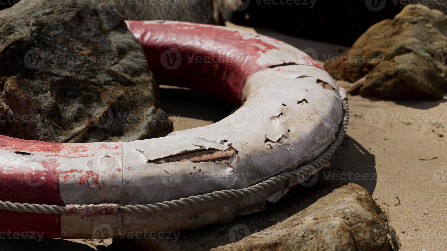 Old damaged lifebuoy on sand photo