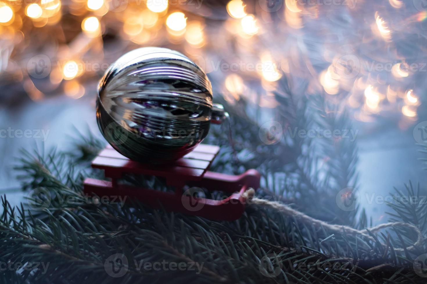 composición navideña con trineo pequeño y bola de navidad en el árbol de navidad. fondo bokeh. foto