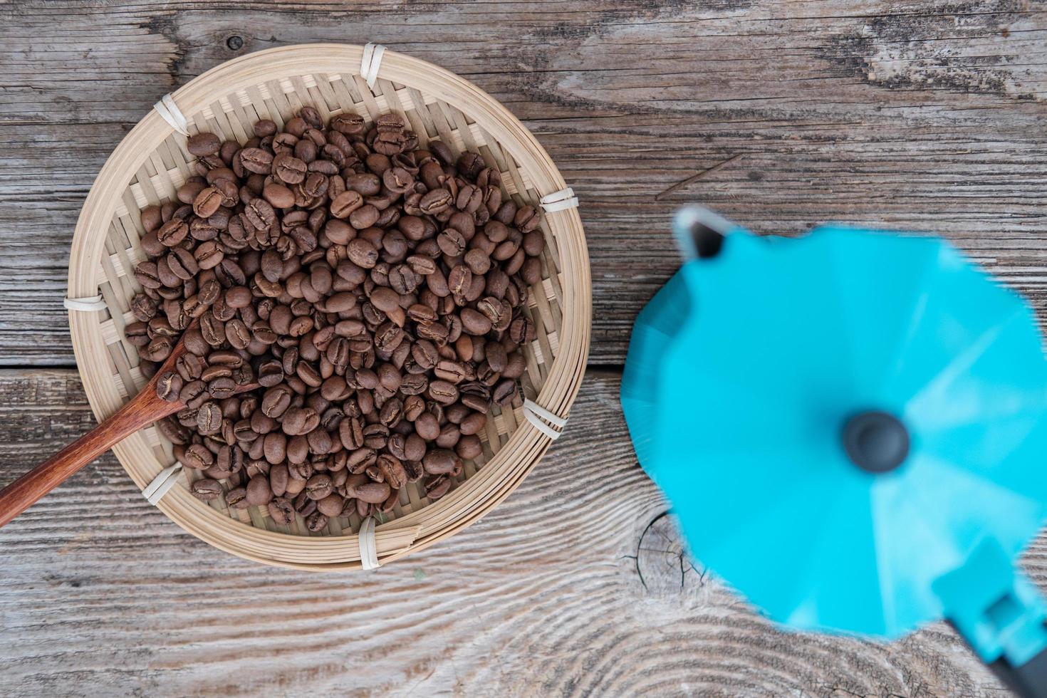 Cafetera de géiser azul y granos de café tostados en el fondo de una vieja placa de madera foto