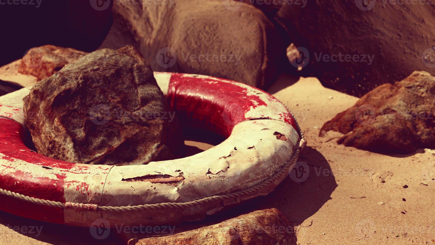 old Life Buoy on sand in sunset photo