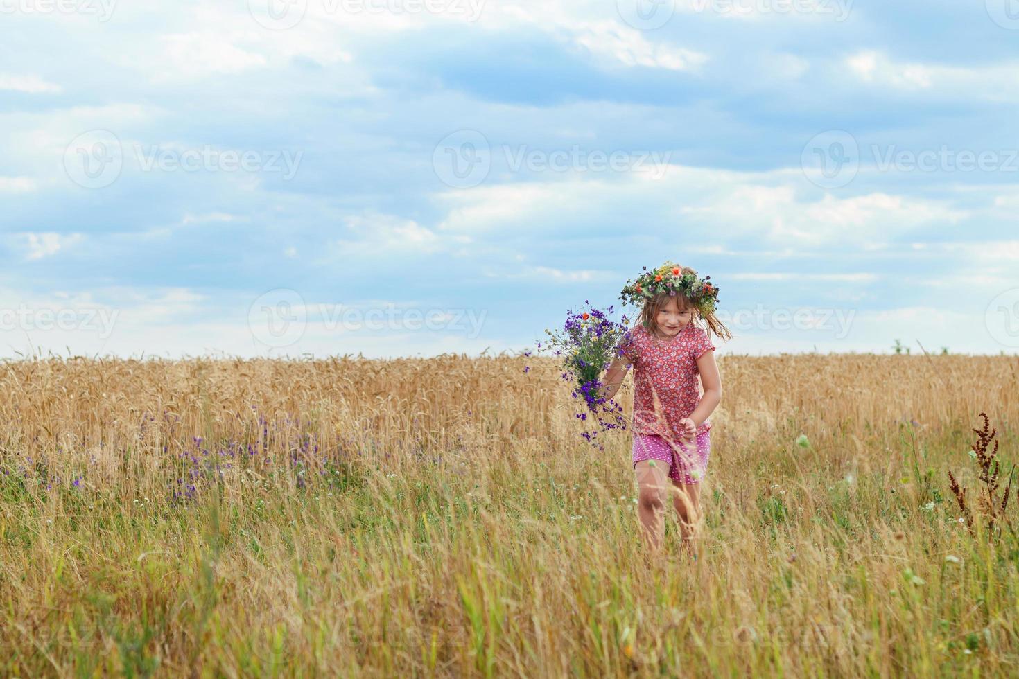 beautiful little girl with a wreath in the wheat field photo
