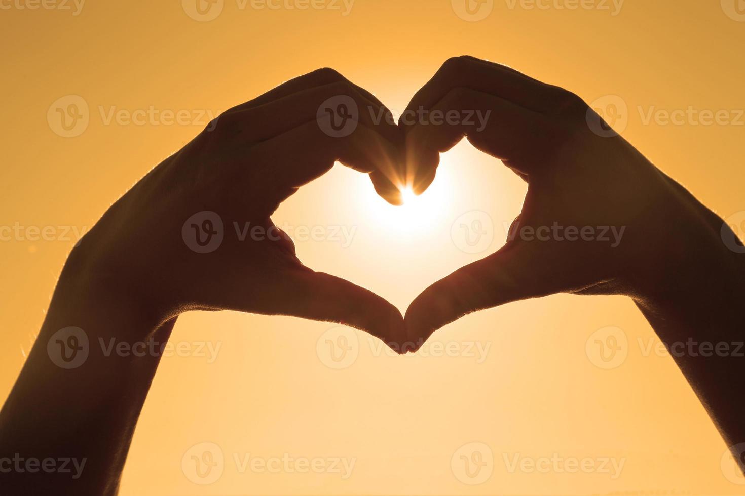 Hand shaped heart against sunset. Valentines day concept photo