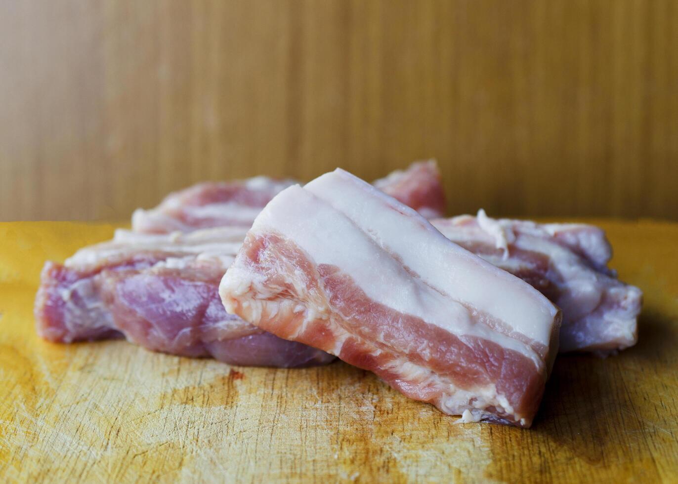 Fresh raw pork belly macro close up on wood cutting board photo