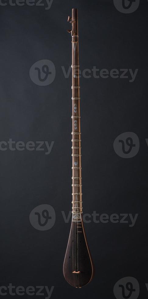 ancient Asian stringed musical instrument on black background with backlight photo