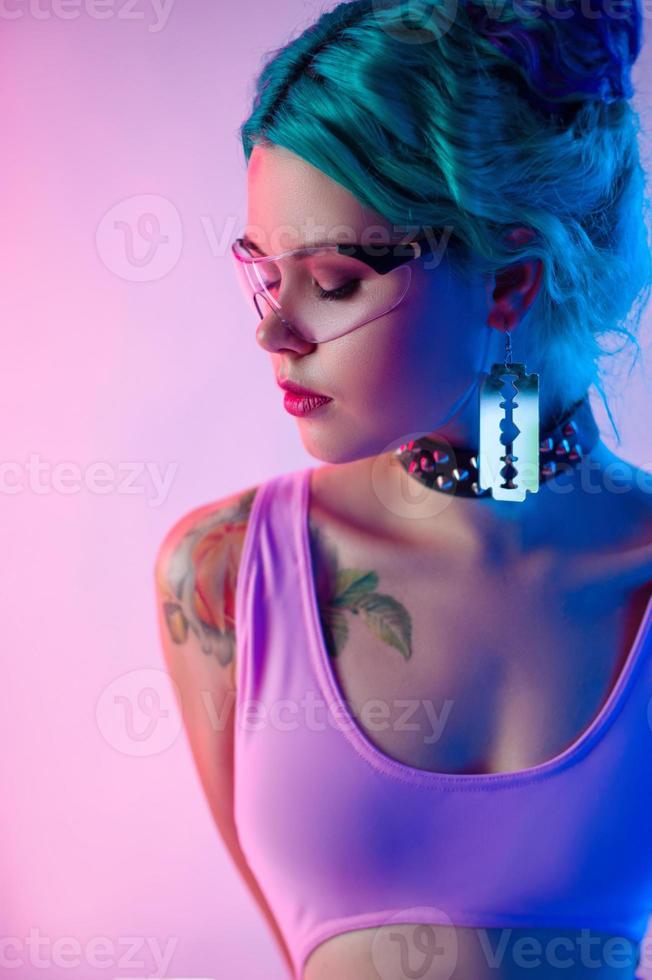 retrato de una mujer brillante con cabello azul en gafas transparentes con luz de neón foto