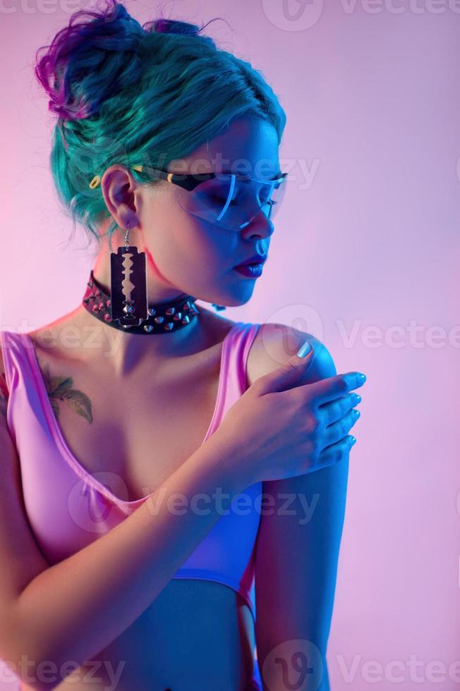 retrato de una mujer brillante con cabello azul en gafas transparentes con luz de neón foto
