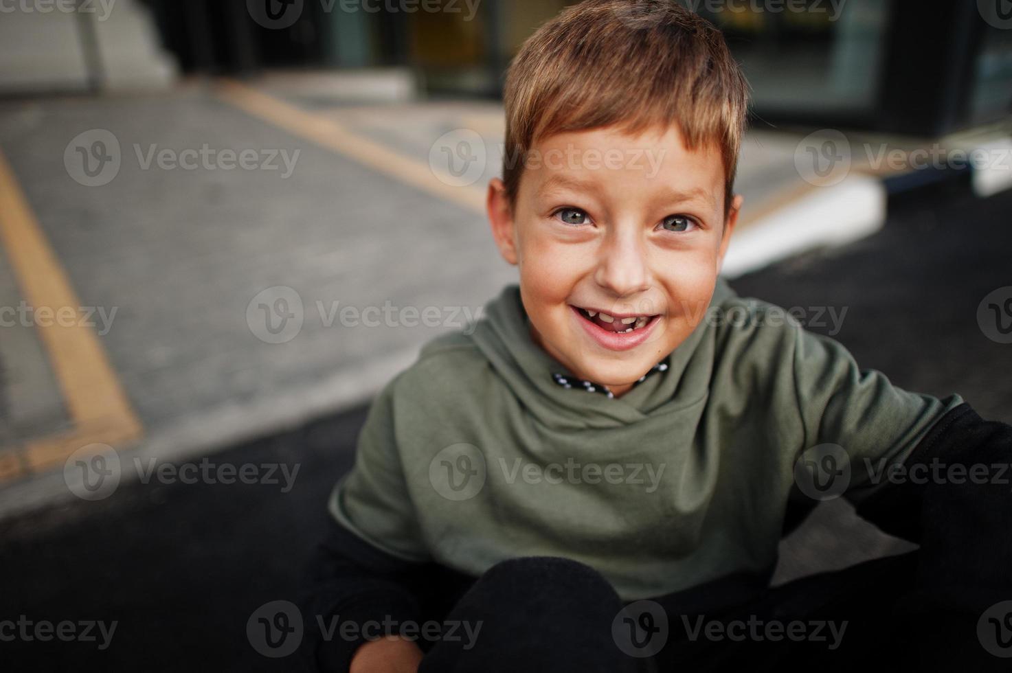 Cierra el retrato de un niño sentado sonriente con traje deportivo. foto