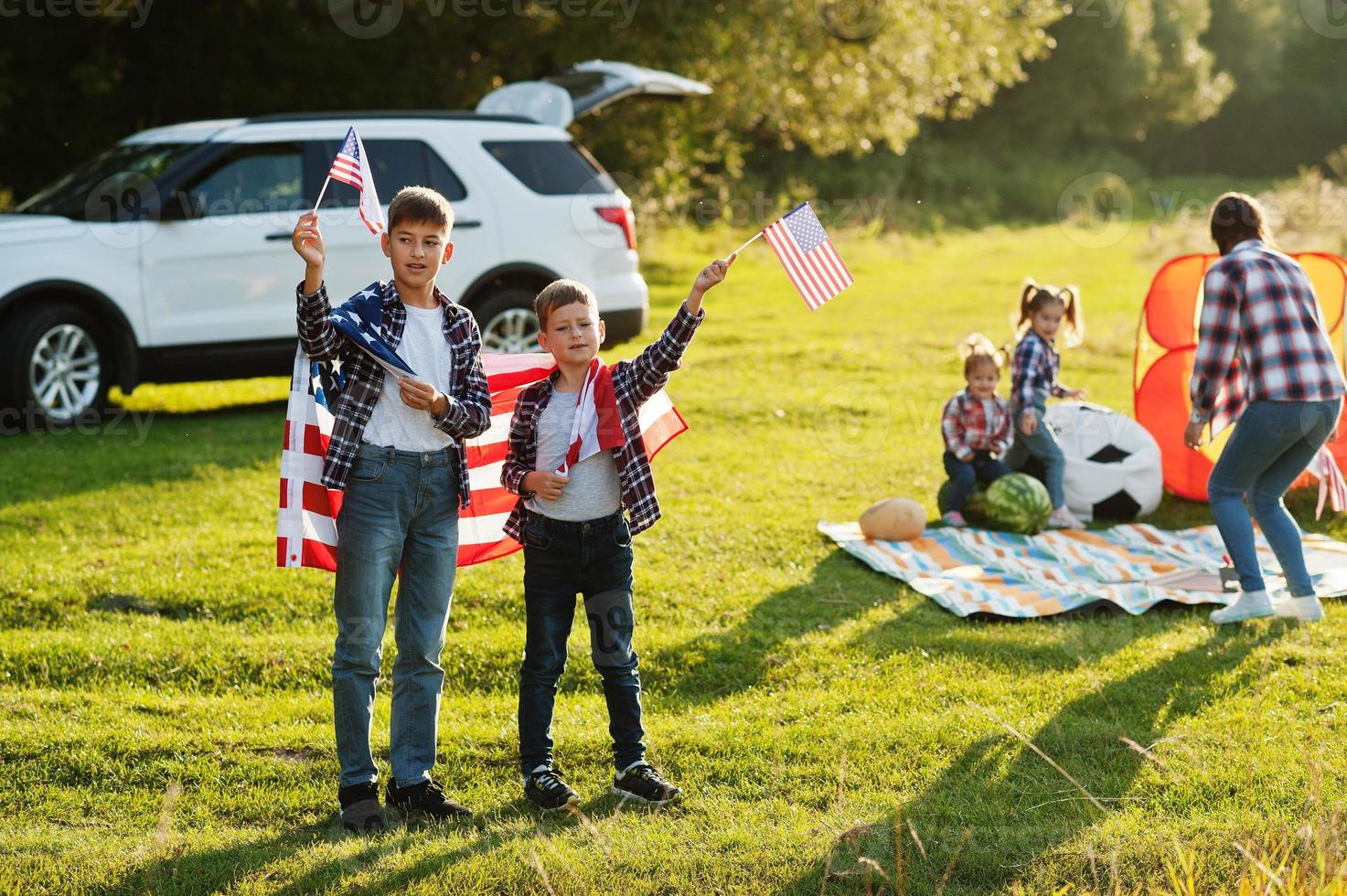 familia americana madre y cuatro hijos. con banderas de estados unidos. América celebrando. foto