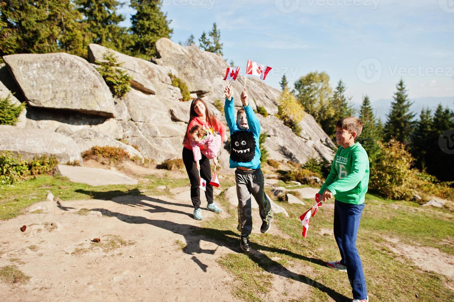 Happy Canada Day. Family of mother with three kids hold large Canadian flag celebration in mountains. photo