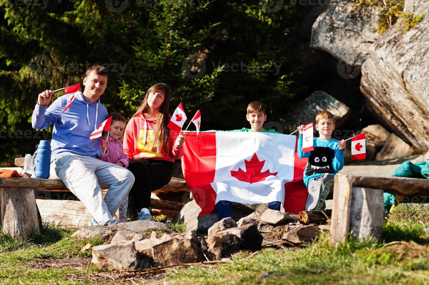 Happy Canada Day. Family with large Canadian flag celebration in mountains. photo